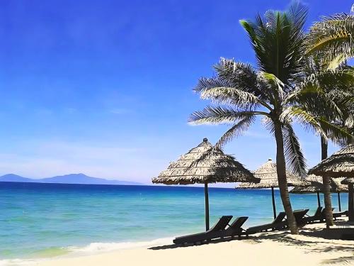 a beach with chairs and palm trees and the ocean at Happy Life Memories Hoi An Hotel & Spa in Hoi An