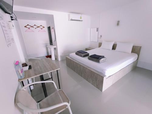 a white bedroom with a bed and a chair at Saan Rak Resort in Prachuap Khiri Khan