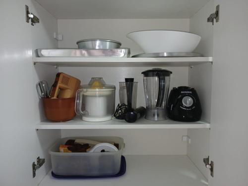 ein Regal mit verschiedenen Küchenutensilien darauf in der Unterkunft AP 1 Dorm Ponta da Praia Santos SP in Água Boa