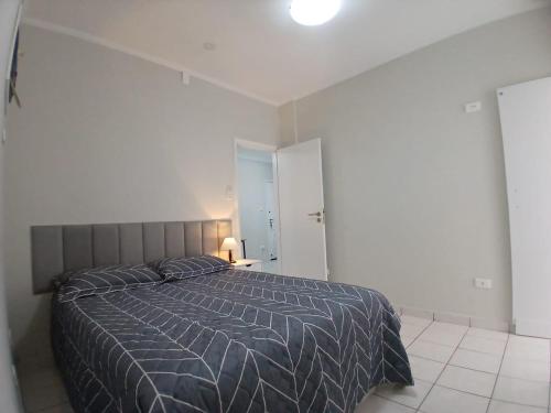 ein Schlafzimmer mit einem großen Bett in einem weißen Raum in der Unterkunft AP 1 Dorm Ponta da Praia Santos SP in Água Boa