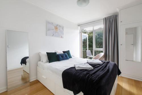 a white bedroom with a large bed and a window at 1 bedroom Boutique in St Kilda East with secure parking in Melbourne