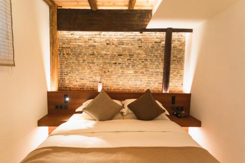 a bedroom with a large bed with a brick wall at Jingdezhen Taoyi Shangnong Hotel in Jingdezhen