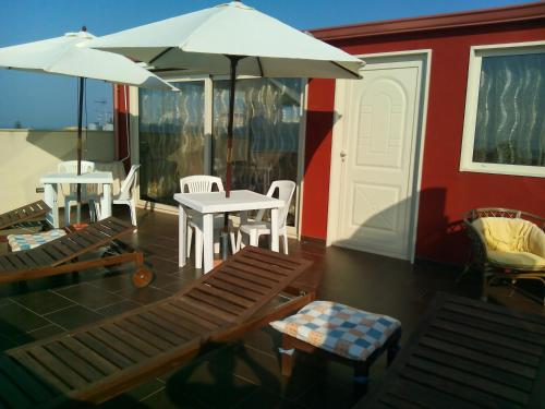 a patio with a table and chairs and umbrellas at Spiagge Iblee in Marina di Ragusa