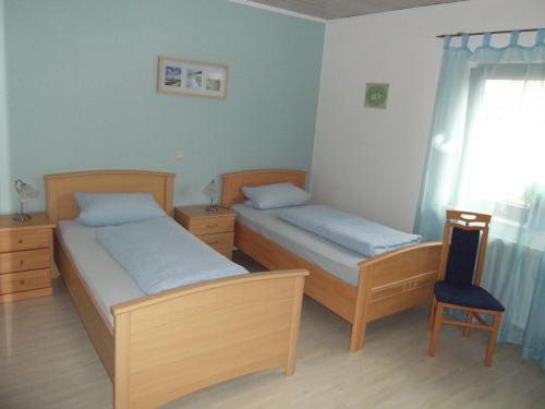 a bedroom with two beds and a chair and a window at Pension und Weingut Hirschhof in Offenheim