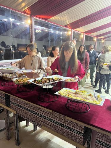 a group of people standing around a table with plates of food at Kylie magic camp in Wadi Rum