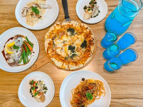 a table with plates of food and a pizza at The Glory Hotel and Residence Clark Pampanga in Mabalacat