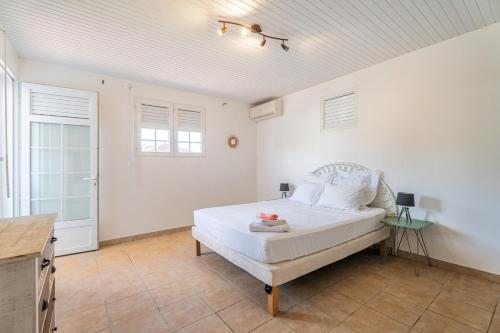 Un dormitorio con una cama en una habitación blanca. en Villa Babaïa, A peaceful oasis, en Le Diamant
