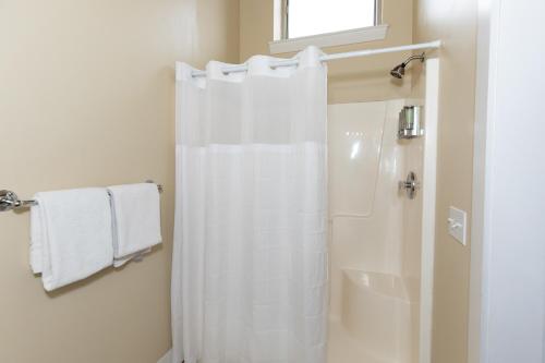 a bathroom with a shower with a white shower curtain at The Jazz Club Downtown Sandusky in Sandusky