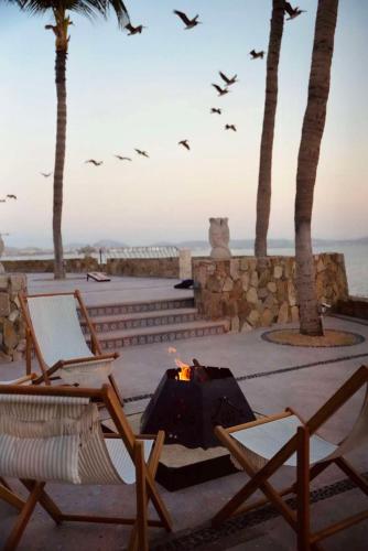 a fire pit with chairs and palm trees and birds at One&Only Palmilla in San José del Cabo