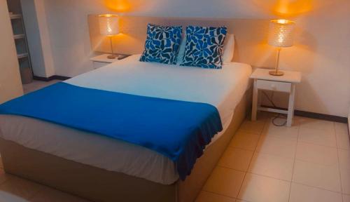 a bedroom with a bed with blue pillows and two lamps at Cantinho das Oliveiras in Geres