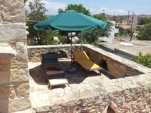 a group of chairs and an umbrella on a stone wall at O Ilios House in Pitsidia