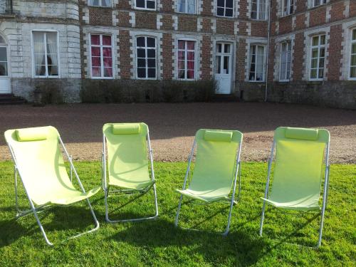 two chairs sitting in the grass in front of a building at Chambres d'hôtes & Gîtes du Château de Grand Rullecourt in Grand Rullecourt