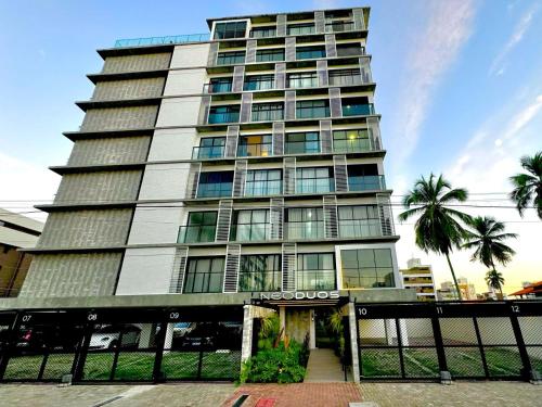 a tall building with palm trees in front of it at Flat vista para o mar in Cabedelo