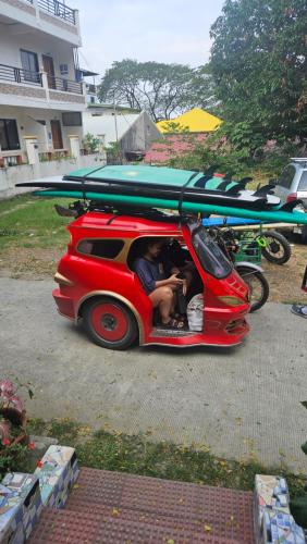 a small red car with a surfboard on top of it at Lokal Home Hostel in San Juan