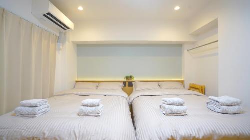 two beds in a room with towels on them at Yuina Hotel Shinjuku in Tokyo