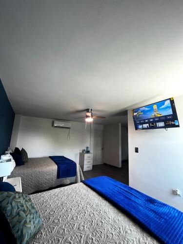 a bedroom with two beds and a flat screen tv at AXEL Suites Departamento 1A in Delicias
