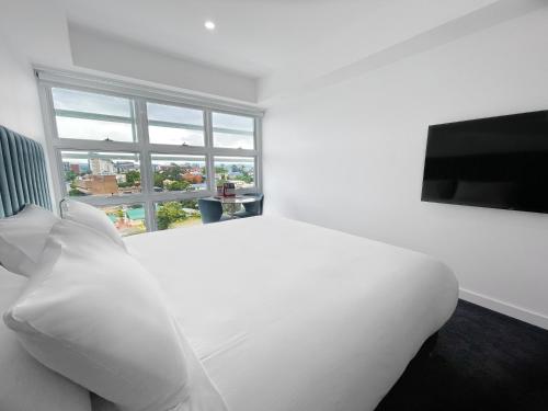 a white bedroom with a large white bed and a window at Swiss-Belhotel Woolloongabba Brisbane in Brisbane
