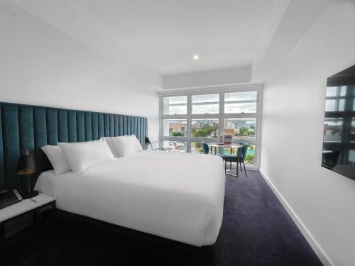 a bedroom with a large white bed and a table at Swiss-Belhotel Woolloongabba Brisbane in Brisbane