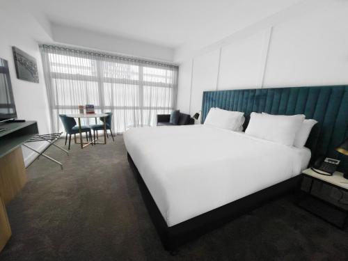 a bedroom with a large white bed and a table at Swiss-Belhotel Woolloongabba Brisbane in Brisbane