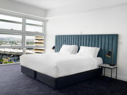 a large white bed in a room with a window at Swiss-Belhotel Woolloongabba Brisbane in Brisbane