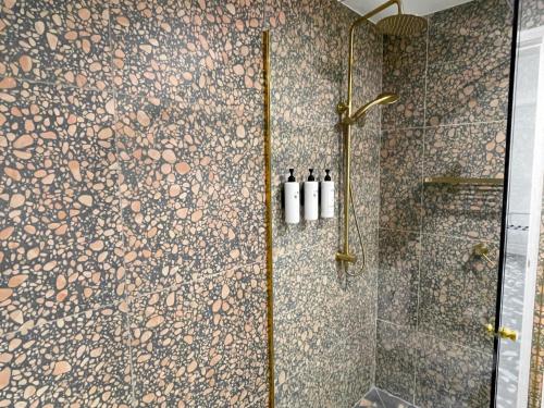 a bathroom with a shower with a stone wall at Swiss-Belhotel Woolloongabba Brisbane in Brisbane