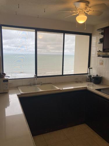 a kitchen with a sink and two large windows at Departamento 4 habitaciones 12 personas vista al mar 8vo piso Playa Almendro in Tonsupa