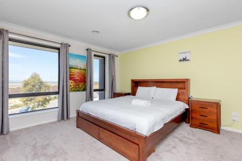 a bedroom with a bed and a large window at Spacious Double Story Family House with Amazing City Views in Point Cook
