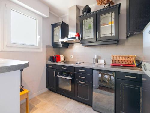 une cuisine avec des armoires noires et un comptoir dans l'établissement Charmant T2 au Centre du Touquet, Balcon et Confort - FR-1-821-33, à Le Touquet-Paris-Plage