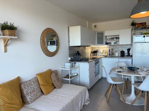 Il dispose d'une cuisine et d'un salon avec un canapé et une table. dans l'établissement Appartement cosy avec vue mer, parking privé, 2 chambres - FR-1-323-569, à Saint-Hilaire-de-Riez