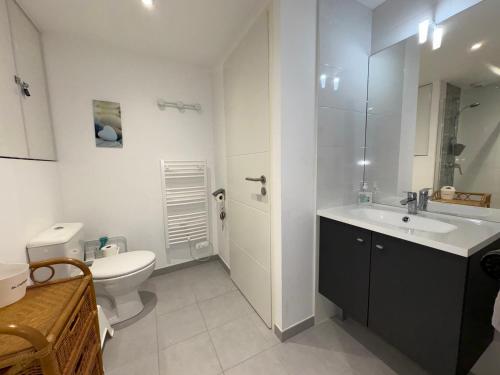 une salle de bain blanche avec des toilettes et un lavabo dans l'établissement Appartement cosy avec vue mer, parking privé, 2 chambres - FR-1-323-569, à Saint-Hilaire-de-Riez