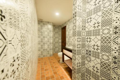a bathroom with a toilet and a tiled wall at Villa Deux Rivieres Hotel in Luang Prabang