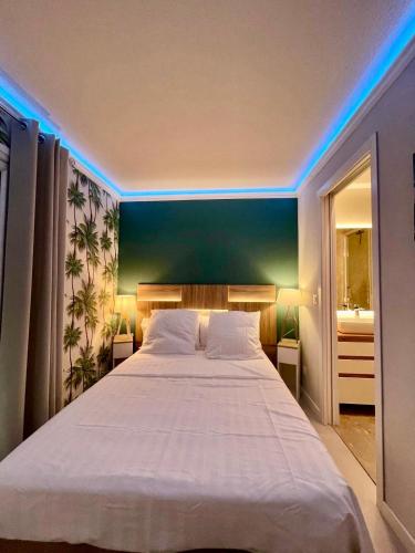 - une chambre avec un grand lit blanc et des lumières bleues dans l'établissement Azuria, à Cannes