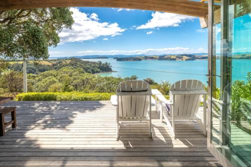 a deck with two chairs and a view of the water at The Sanctuary Couples Retreat in Waiheke Island