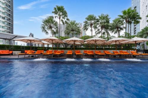 a swimming pool with orange chairs and umbrellas at Bangkok Marriott Hotel Sukhumvit in Bangkok