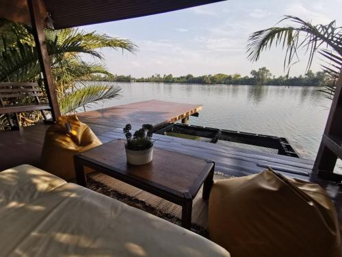 a house with a table and a view of a lake at บ้านพระจันทร์เวียน - House of moon phase in Chachoengsao