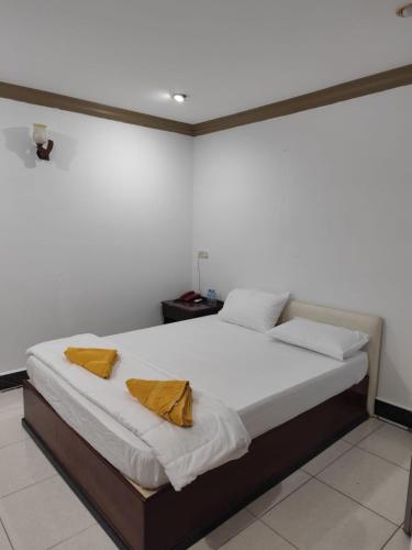 a bedroom with a large bed with two yellow pillows at Hotel Selver Shinn & Restaurant in Phnom Penh
