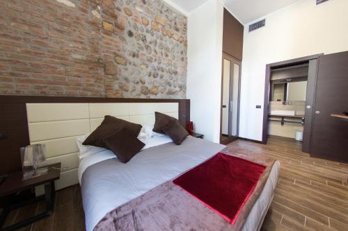 una camera con un grande letto e un muro di mattoni di Arena Luxury Rooms a Verona