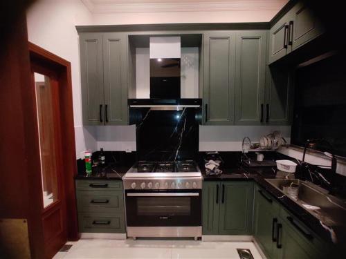 a kitchen with green cabinets and a stove top oven at Mehmood Palace in Lahore
