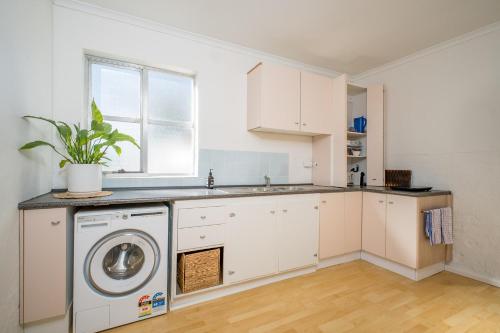 a white kitchen with a washing machine in it at American Hotel Creswick in Creswick
