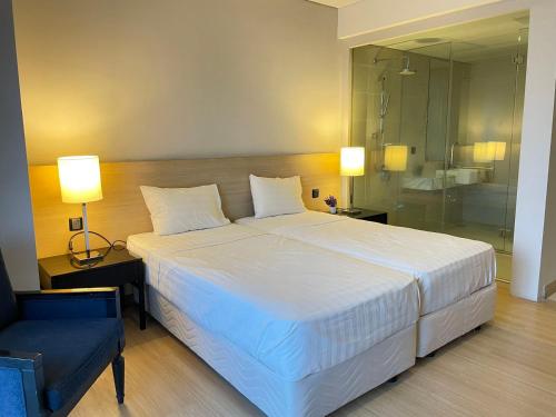 a bedroom with a large white bed and a chair at The Straits Suites by Ciconia in Melaka