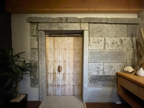 a wooden door in a room with a stone wall at 古民家ウェルネスビレッジ青梅 成木の社 Nariki no Mori in Ome