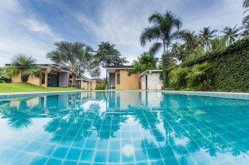 a swimming pool in front of a house with palm trees at 3 TIGERS Resort & Hostel in Chaweng