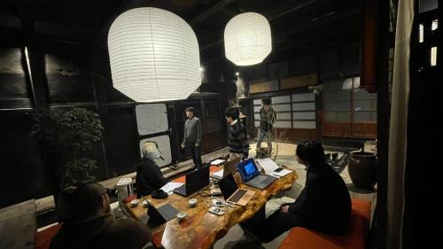 a group of people sitting around a table with laptops at 古民家ウェルネスビレッジ青梅 成木の社 Nariki no Mori in Ome