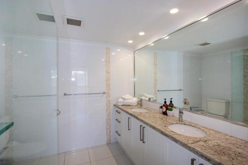 a white bathroom with two sinks and a shower at Sandcastles On Currumbin Beachfront, Gold Coast in Gold Coast
