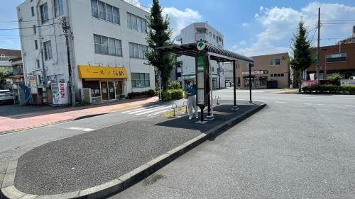 a person standing at a bus stop on a street at 古民家ウェルネスビレッジ青梅 成木の社 Nariki no Mori in Ome