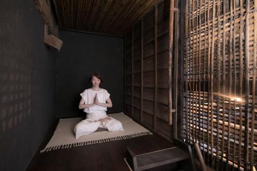 a woman sitting in a room doing meditation at 古民家ウェルネスビレッジ青梅 成木の社 Nariki no Mori in Ome