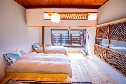 two beds in a room with a window at 真鶴海の見える古民家風ジャパニーズルームapartment Hotel途乃中W2 in Manazuru