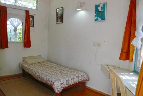 a room with a bed in the corner of a room at New Creation Guest House in Auroville