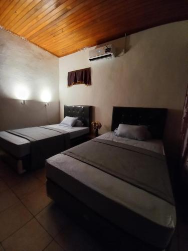 a bedroom with two beds and a ceiling at Bunaken Blesshi Guest House in Bunaken
