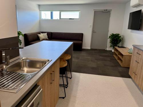a kitchen with a sink and a living room at Brighton Hotel Motel in Pontville